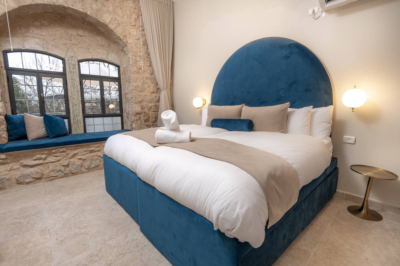 Suite bedroom with arched velvet headboard and stone alcove