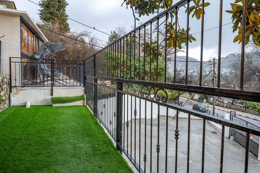 Terrace lawn corner with railing and hillside view