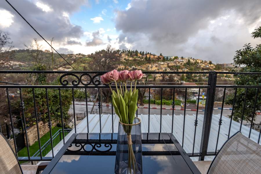 Balcony table with flowers overlooking cloudy hillside