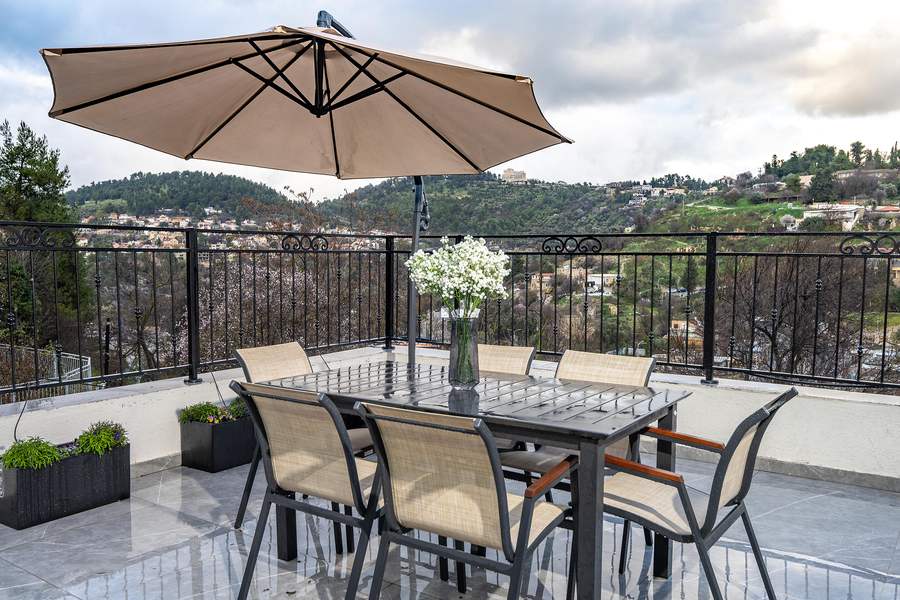 Terrace dining table with umbrella and hillside view